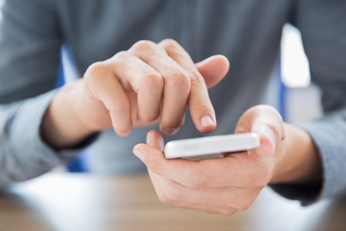 Close-up of male hands holding smartphone and touching screen. Businessman texting message or networking