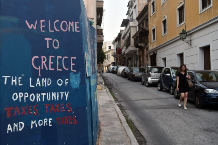A woman walks by a slogan on a wall in Athens on May 12 , 2017.<br /> According to official estimates, Greece's economy has shrunk by 25 percent since the start of the fiscal and debt crisis in 2010, with successive governments forced to carry out unprecedented cuts to wages and pensions. The Greek parliament adopted on May 18, 2017 a new round of austerity cuts which the government hopes will secure a pledge of debt relief and loan disbursements by EU-IMF creditors this month.<br /> / AFP PHOTO / LOUISA GOULIAMAKI (Photo credit should read LOUISA GOULIAMAKI/AFP/Getty Images)
